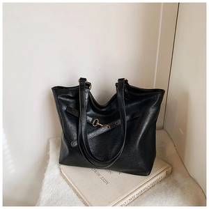Detail of vintage black tote bag with buckle strap on books for a retro aesthetic look