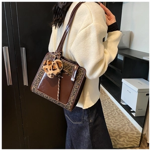 Detail of dark brown tote bag with leopard print side panels and plush heart charm