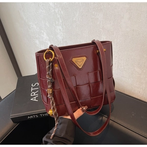 Detalle de bolso tote de cuero PU trenzado color burdeos con logo dorado y cuerda