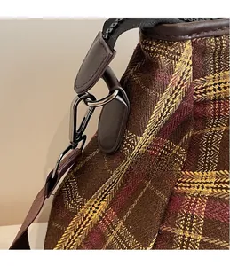Détail macro des crochets en métal et des bordures en cuir sur le sac de voyage à carreaux