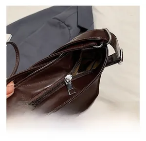 Detail of silver zipper, D-ring buckle, and striped lining on dark brown leather tote bag