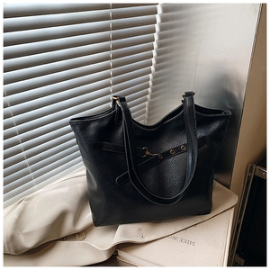 Macro detail of black pebble texture faux leather tote bag with gold metal buckle