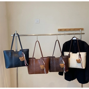 Detailed close-up of large leather tote bags with contrast stitching and bear charms