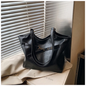 Close-up of black PU leather tote bag with grainy texture and golden metal buckle detail
