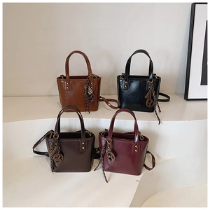 Vue détaillée de quatre sacs seaux en cuir brillant coloré avec des charms à glands