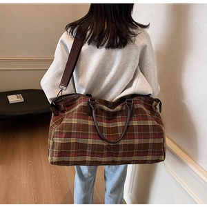 Détail du grand sac de voyage à carreaux avec poignées en cuir et bandoulière réglable