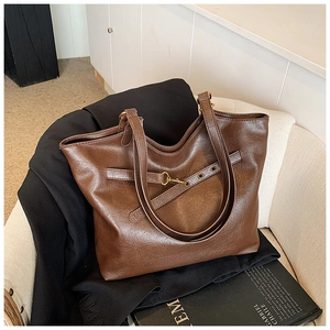 Detail of vintage brown leather tote bag with decorative buckle strap and metal clasp