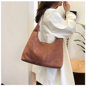 Close-up of a brown matte suede tote bag styled with a white outfit in a minimalist setting