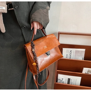 Détail d'un sac à main marron vintage avec boucle argentée et ornement tressé élégant