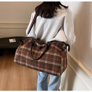 Gros plan d'un grand sac de voyage à carreaux avec bandoulière réglable sur modèle