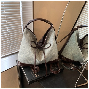 Detail of vintage denim tote bag with leather trim and decorative bow drawstring