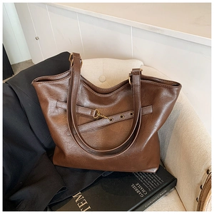 Close-up of retro brown tote bag with pebble leather texture and metal buckle detail