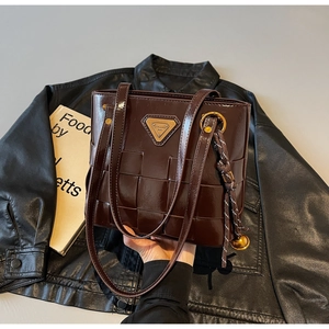 Detalle del bolso tote trenzado marrón oscuro con textura de cuero brillante y logo