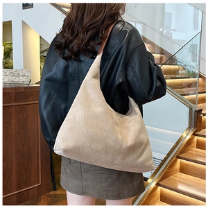Detail of matte beige suede tote bag with brown leather handles worn by a model