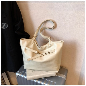 Detail of off-white tote bag with fine leather texture on a silver suitcase