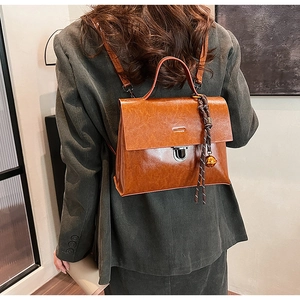 Détail d'un sac à dos vintage en cuir caramel avec fermoir rotatif argenté et cloche