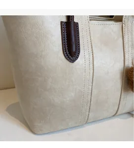 Close-up of beige tote bag showing high-quality leather texture and detailed stitching