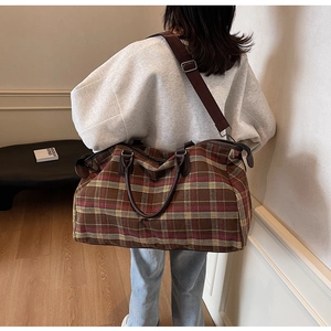 Vue de dos d'un mannequin portant un grand sac de voyage à carreaux marron avec anses