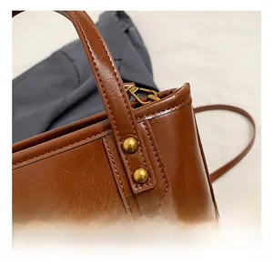Détails des rivets dorés et texture cuir ciré de ce sac à main marron chic