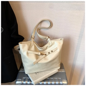 Detail of cream faux leather tote bag with decorative strap and metal snap button