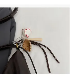 Close-up of a vintage baseball charm featuring a mini bat and glove on a brown leather bag