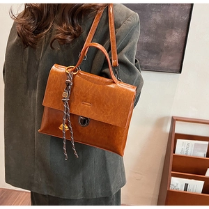 Détail du sac à main en cuir PU marron avec fermoir en métal vintage et breloque cloche tressée