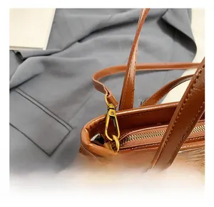 Détail du crochet pivotant doré et de la fermeture éclair sur le sac en cuir marron
