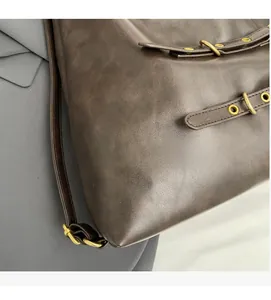 Close-up of soft brown faux leather texture with bronze metal buckle and ring detail