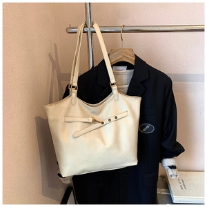 Detail of off-white tote bag featuring gold buckle hardware and premium leather texture