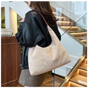 Detail view of large beige suede-textured tote bag with a brown leather shoulder strap