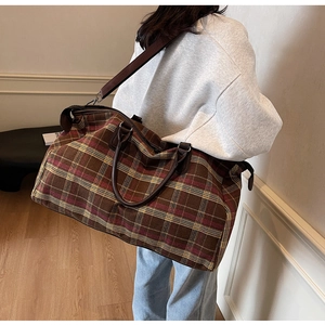 Grand sac de voyage à carreaux avec bandoulière réglable utilisé par un modèle