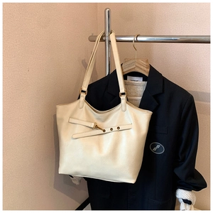 Detail of cream leather tote bag with decorative horizontal belt and metal buckle