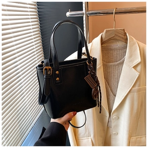 Détail du sac seau en cuir noir élégant avec finitions dorées et breloque abaque