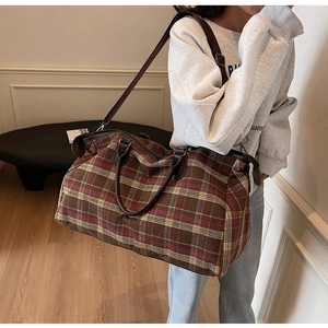 Vue détaillée du grand sac de voyage à carreaux avec poignées en cuir et sangle