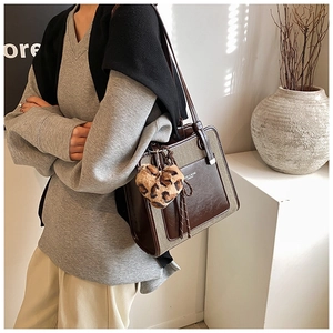 Detail of canvas tote bag with brown leather pocket and leopard print heart charm