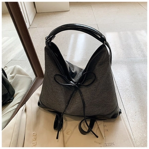 Top view of a minimalist grey fabric tote bag with black leather accents and bow detail
