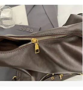 Close-up of premium dark chocolate leather texture and smooth golden metal zipper detail
