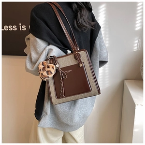 Detail of a contrast color tote bag featuring leopard heart pendant and leather pocket