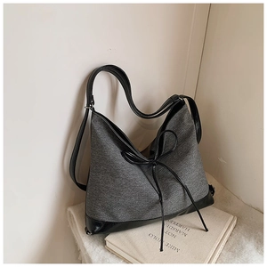 Detail of grey fabric tote bag with black leather patchwork and delicate bow decoration