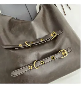 Detail of dark brown leather tote bag with polished gold hardware and buckle accents