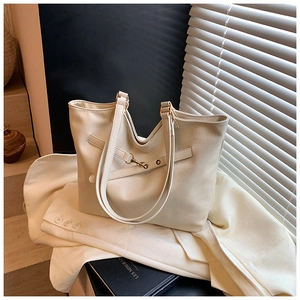 Detail of a minimalist beige tote bag with metallic buckle and soft leather texture