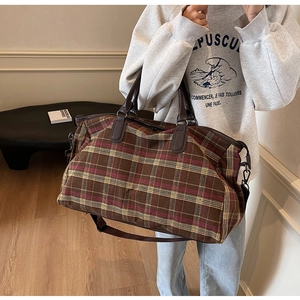 Gros plan détaillé du sac de voyage à carreaux marron avec poignées en cuir et sangle