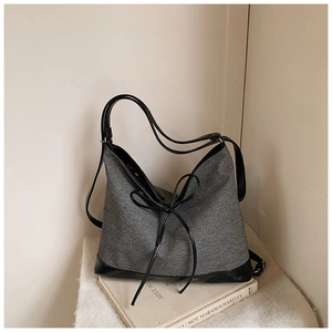 Detail showing the textured grey fabric and black leather handles of the tote bag