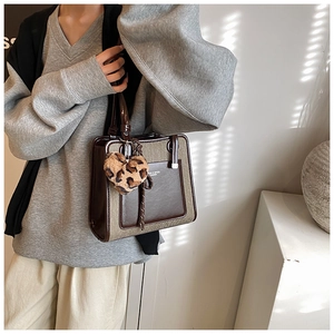 Detail of a vintage-style tote bag with brown leather and canvas patchwork texture