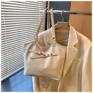 Detail of a large cream white faux leather tote bag hanging in a chic office setting