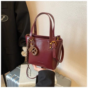 Détail du sac seau en cuir ciré rouge avec poignées et un pendentif donut