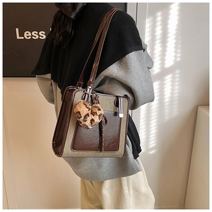 Detail view of contrast color tote bag with plush leopard heart charm for women