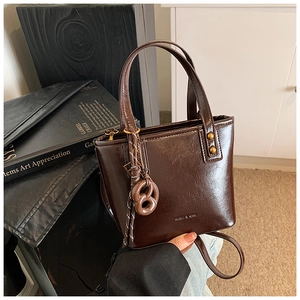 Détail du sac seau en cuir ciré avec clous dorés et breloque bretzel créative