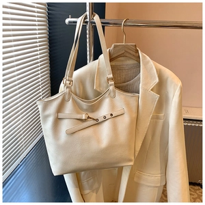 Detail of cream tote bag with gold buckle strap and textured faux leather finish