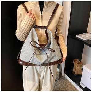 Detailed view of large denim and leather bucket bag worn as a casual backpack